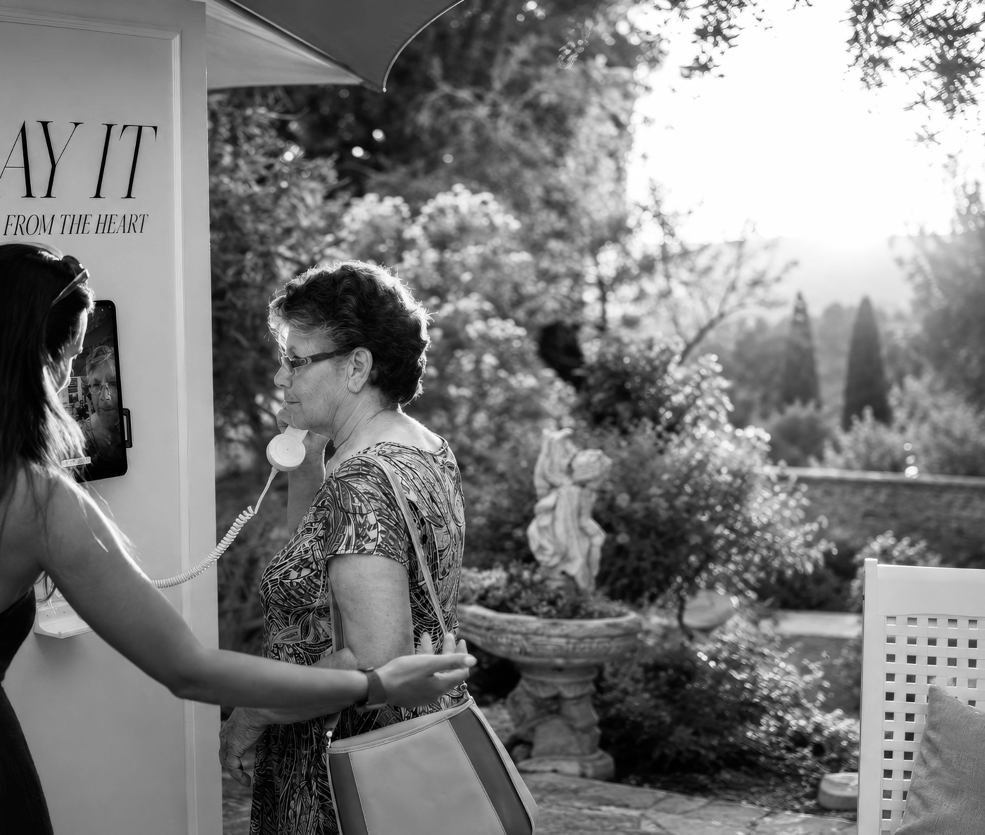 An older guest listening on the Say It phone, in black and white